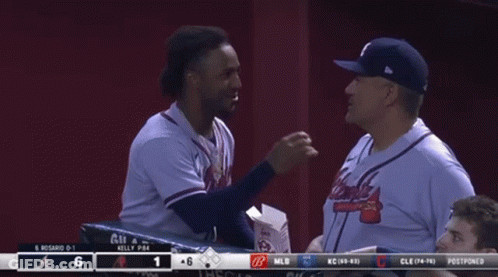 A Man In An Atlanta Braves Jersey Talks To Another Man In A Baseball Dugout GIF