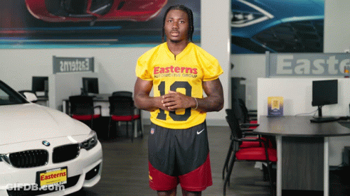 A Man In An Easterns Automotive Group Jersey Stands In Front Of A Bmw GIF