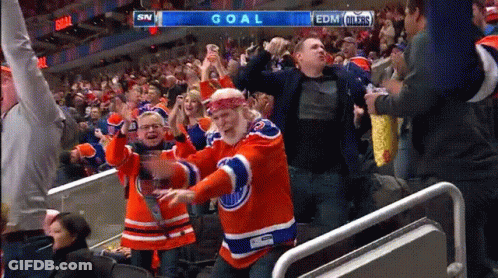 A Man In An Edmonton Oilers Jersey Is Dancing In The Stands At A Hockey Game GIF