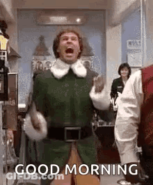 A Man In An Elf Costume Is Screaming And Saying `` Good Morning '' In A Kitchen . GIF