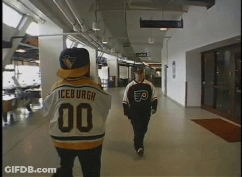 A Man In An Iceburgh Jersey Walks Down A Hallway Next To Another Man GIF
