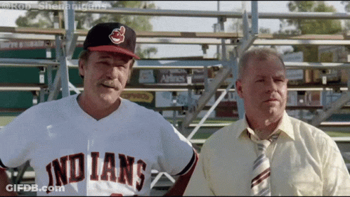 A Man In An Indians Jersey Stands Next To Another Man In A Tie GIF