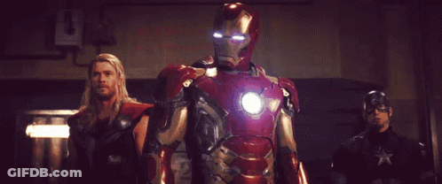 A Man In An Iron Man Suit Stands Between Two Other Men GIF