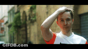 Man In Orange And White Nike Shirt Holding Hand To Forehead GIF
