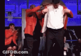 A Man In An Orange Jacket Is Being Lifted By Another Man In A White Shirt GIF