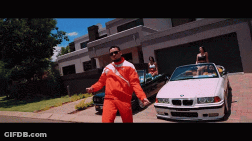A Man In An Orange Jacket Is Standing In Front Of A Bmw GIF