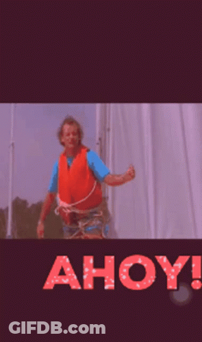 A Man In An Orange Life Vest Is Standing In Front Of A Sign That Says Ahoy ! GIF