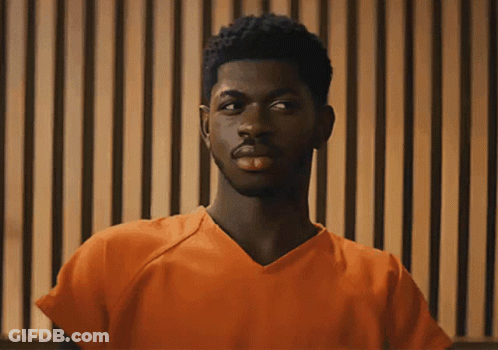 A Man In An Orange Prison Uniform Is Looking At The Camera GIF