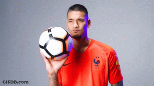 A Man In An Orange Shirt Holds A Soccer Ball In His Hand GIF