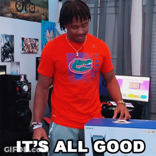 A Man In An Orange Shirt Is Holding A Box That Says " It 'S All Good " GIF