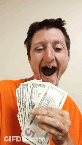 A Man In An Orange Shirt Is Holding A Stack Of 5 Dollar Bills GIF