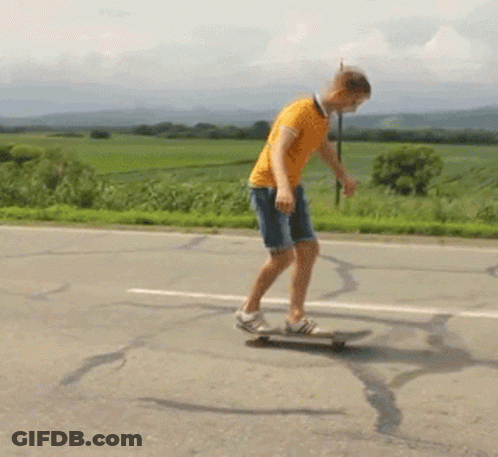 A Man In An Orange Shirt Is Riding A Skateboard Down The Road GIF