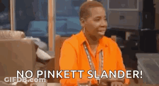 A Man In An Orange Shirt Is Sitting At A Table And Saying No Pinkett Slander . GIF