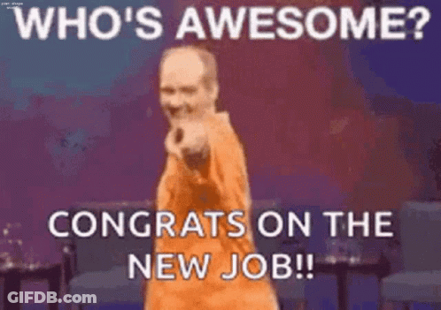 A Man In An Orange Shirt Is Standing On A Stage With His Hands On His Hips And Congratulating Someone On Their New Job . GIF