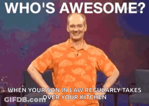 A Man In An Orange Shirt Is Standing With His Hands On His Hips And Says Who 'S Awesome . GIF
