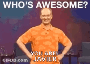 A Man In An Orange Shirt Is Standing With His Hands On His Hips And Smiling . GIF