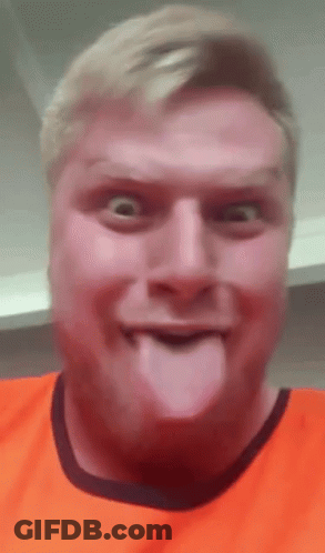 A Man In An Orange Shirt Is Sticking Out His Tongue . GIF