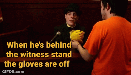 A Man In An Orange Shirt Is Talking To A Man In A Top Hat Behind A Witness Stand GIF