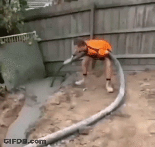A Man In An Orange Shirt Is Using A Hose To Pump Concrete Into The Ground . GIF