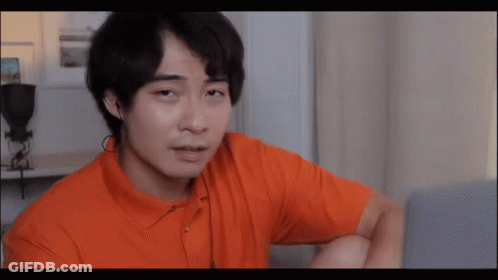 A Man In An Orange Shirt Looks At A Laptop Screen GIF