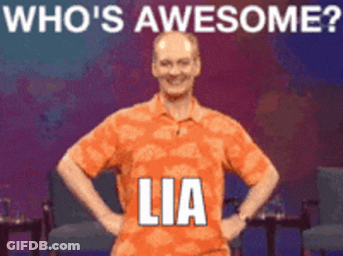 A Man In An Orange Shirt Stands With His Hands On His Hips In Front Of A Sign That Says " Who 'S Awesome Lia " GIF