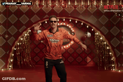 A Man In An Orange Shirt That Says Netflix On It GIF