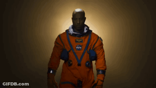 A Man In An Orange Space Suit With A Nasa Patch On His Chest GIF