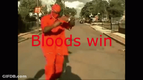 A Man In An Orange Suit Is Walking Down A Street With The Words Bloods Win Written On It GIF