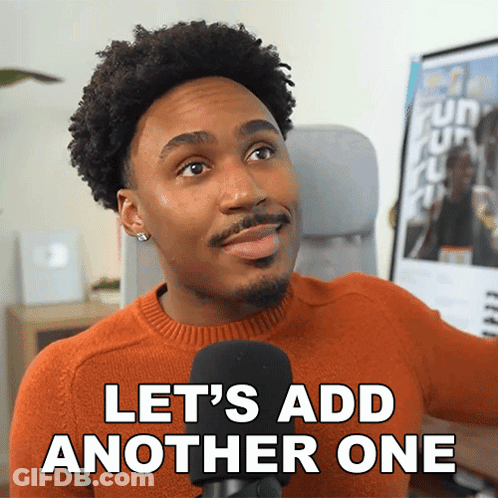 A Man In An Orange Sweater Is Talking Into A Microphone And Says Let 'S Add Another One GIF