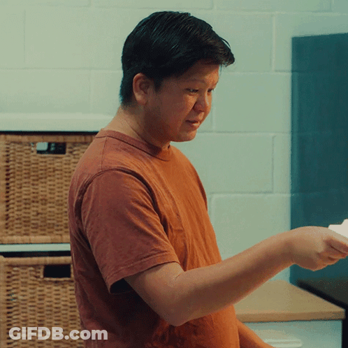 A Man In An Orange T-Shirt Is Holding A Piece Of Paper GIF