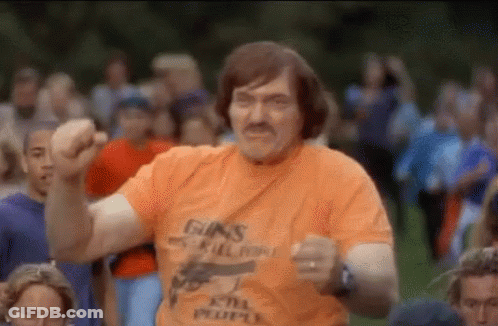 A Man In An Orange T-Shirt With A Gun On It Is Dancing In Front Of A Crowd . GIF