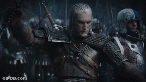 A Man In Armor Is Holding A Sword In Front Of A Group Of Men . GIF