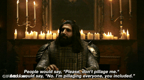 A Man In Armor Is Sitting At A Table With Candles Behind Him GIF