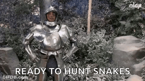 A Man In Armor Is Standing In A Snowy Forest With His Hands On His Hips . GIF