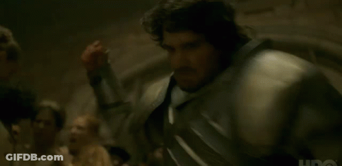 A Man In Armor Is Standing In Front Of A Group Of People In A Dark Room . GIF