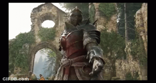 A Man In Armor Is Standing In Front Of A Ruined Building . GIF