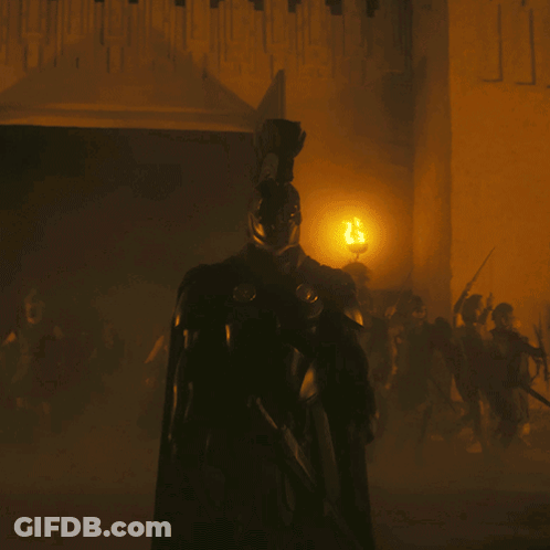 A Man In Armor Is Standing In Front Of A Wall With The Letter J Written On It GIF