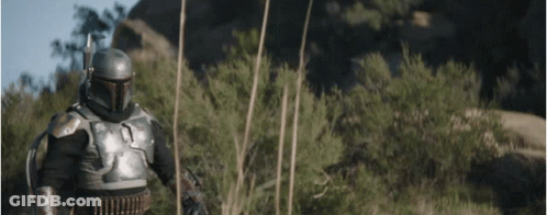A Man In Armor Is Standing In The Middle Of A Field With Trees In The Background . GIF
