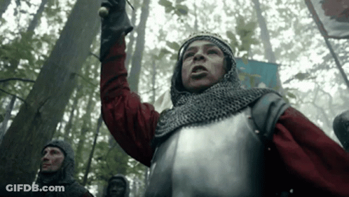A Man In Armor Is Standing In The Middle Of A Forest Holding A Sword . GIF
