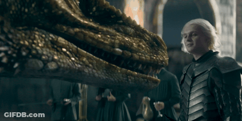 A Man In Armor Is Standing Next To A Dragon GIF
