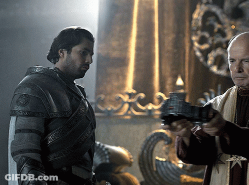 A Man In Armor Is Standing Next To Another Man Who Is Holding A Gun GIF