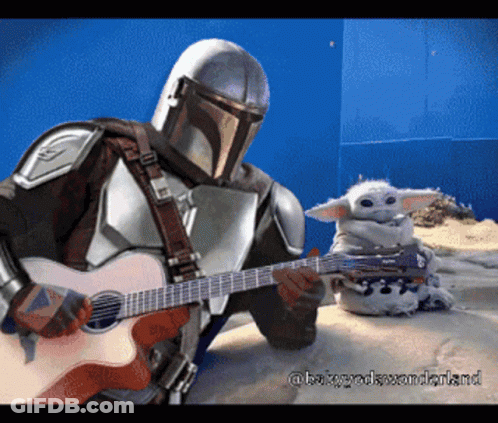 A Man In Armor Playing A Guitar Next To A Baby GIF