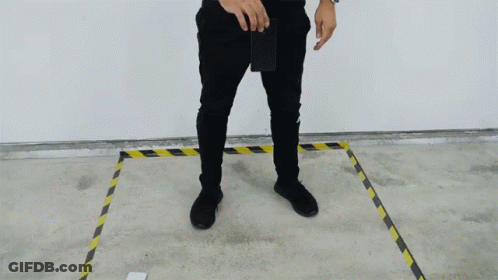 A Man In Black Pants Is Standing In A Yellow And Black Line GIF