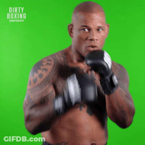 A Man In Boxing Gloves Stands In Front Of A Green Screen With The Words Dirty Boxing Championship On It GIF