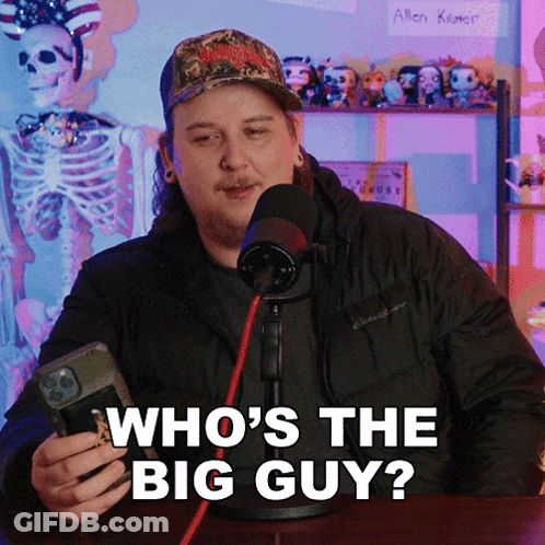 A Man In Front Of A Microphone Is Holding A Cell Phone And Says Who 'S The Big Guy GIF
