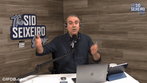 A Man In Front Of A Sign That Says The Sid Seixeiro On It GIF
