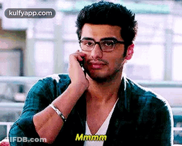 A Man In Glasses Is Talking On A Cell Phone . GIF