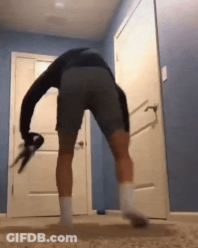 A Man In Gray Shorts And White Socks Is Dancing In Front Of A White Door GIF