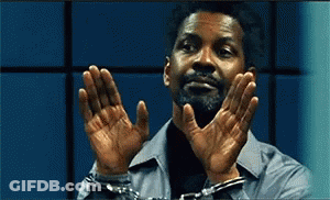A Man In Handcuffs Holds His Hands Up In Front Of His Face . GIF