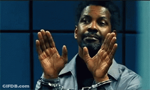 A Man In Handcuffs Holds His Hands Up In Front Of His Face . GIF